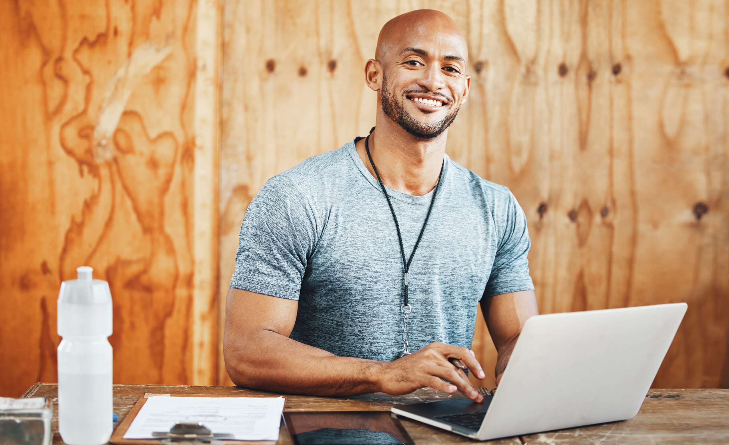 Laptop, portrait and coach with man in gym for fitness instructor, planning and digital membership record. Online schedule, personal trainer and equipment manager with person in health facility.