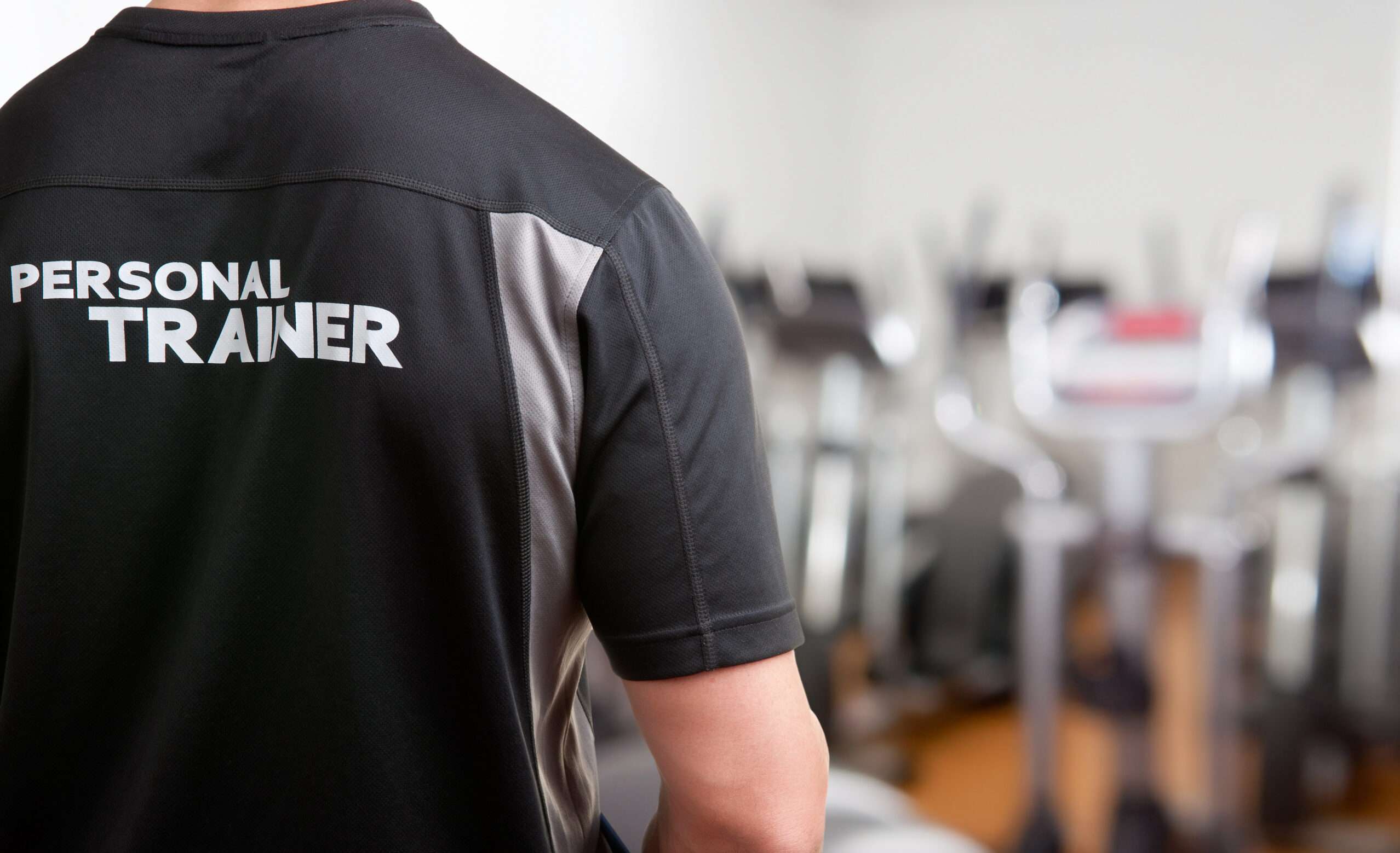 Personal Trainer, with his back facing the camera, looking at a gym