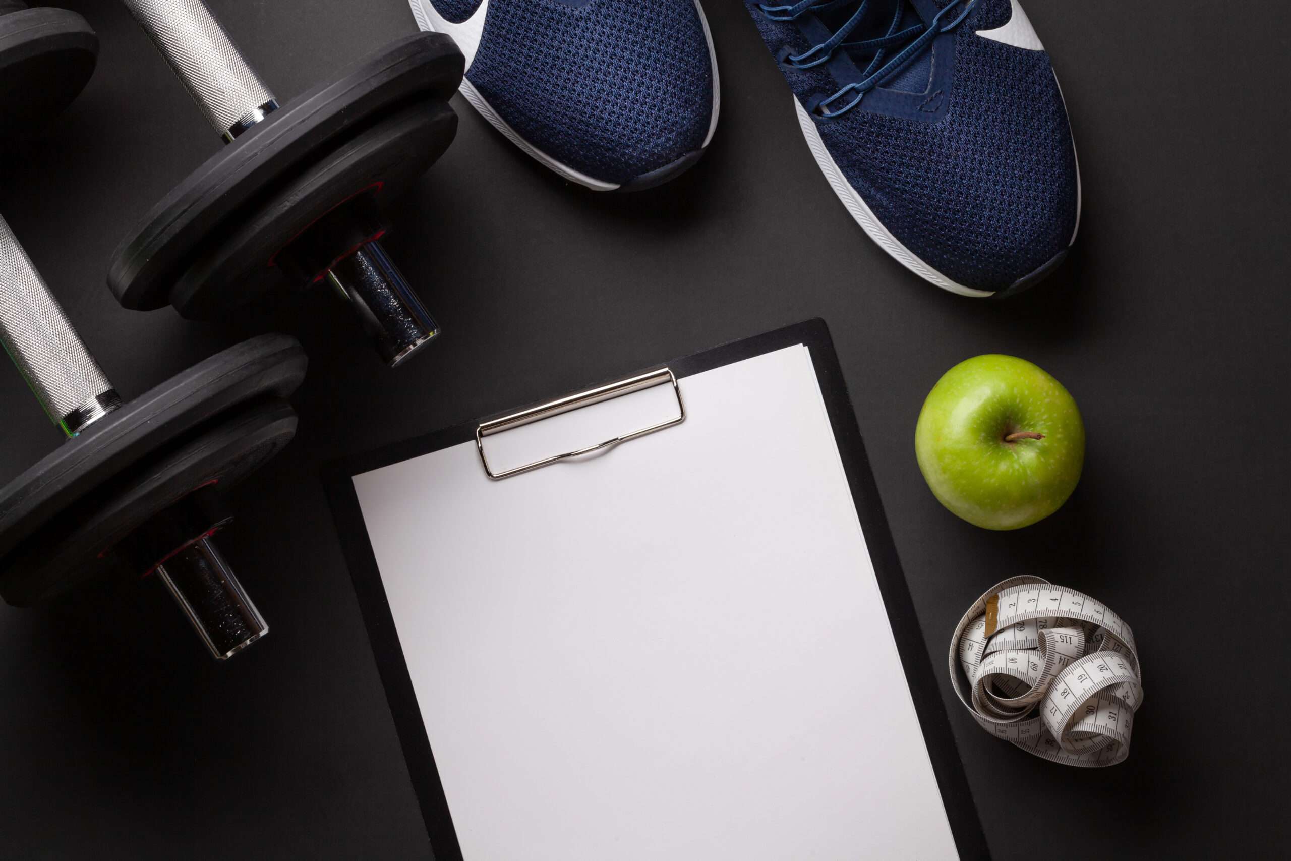 Sneakers, apple and dumbbells. Sport, fitness and healthy lifestyle background. Top view flat lay with copy space